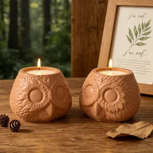 Paar schattige uil geurkaarsen in rustieke keramische houders, perfect voor de herfst huisdecoratie.