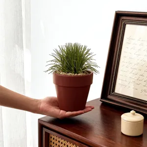Vue détaillée d'une plante artificielle en pot rond en terre cuite sur un meuble en bois.