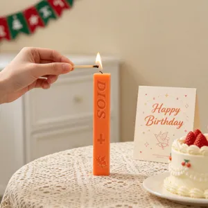Close-up of orange scented pillar candle with embossed DIOS lettering and cute cupids.