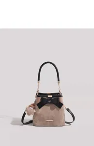 Close-up detail of the women suede bucket bag featuring a black bow and braided handle.