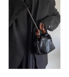 Elegant black crinkled leather handbag featuring unique amber bead handle and chic chain strap.