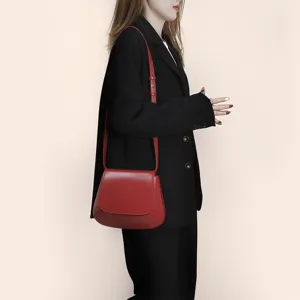Detail view of the elegant red leather saddle bag, showcasing the smooth texture and strap.