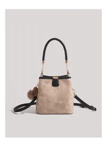 Canvas and leather bucket bag detail showing braided handle, gold hardware, and chic fuzzy charm.