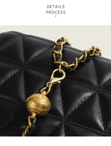 Close-up detail of black quilted leather crossbody bag with vintage gold chain and metal ball.
