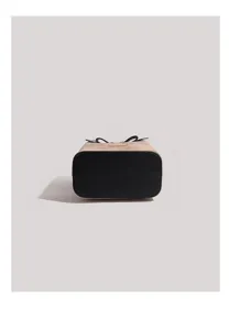 Detail view of women retro bucket bag with contrast black base and chic bow accent.