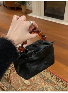 Vintage black leather handbag with chunky amber bead handle, chic retro style bag.