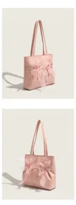Détail de sac cabas rose avec rubans nœuds doux, design plissé et double bandoulière.