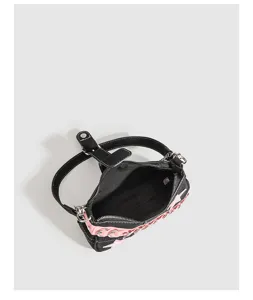 Detailed view of the black and pink Y2K shoulder bag featuring metal rings and lining.
