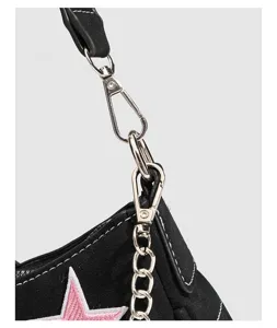 Close up of black Y2K shoulder bag detail, silver hardware, chain strap, pink star patch.