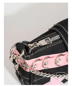 Y2K punk style black and pink shoulder baguette bag detail with metal chain and rings.