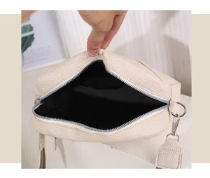 Detailed view of an off-white PU leather crossbody bag with zipper and wide strap.