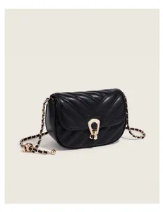 Black quilted crossbody bag detail, featuring golden chain strap and unique metal clasp.