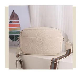 Close-up detail of beige PU leather crossbody bag with chic wide striped strap and zipper.