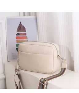 Beige litchi pattern PU leather crossbody bag for women with stylish striped wide strap.