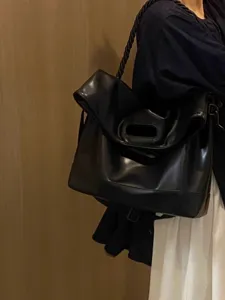 Large black soft leather shoulder bag for women, minimalist commuter tote bag with woven strap.