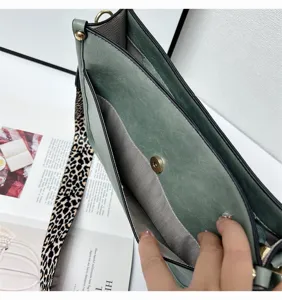 Detail view of green shoulder bag with leopard wide strap and multiple compartments.