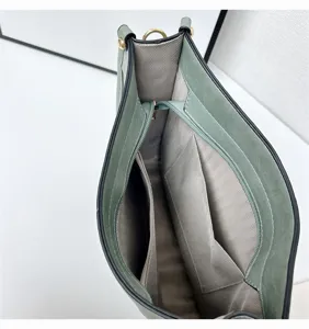 Green shoulder bag interior detail showing spacious compartments, zipper pocket and lining.