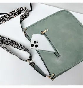 Green shoulder bag with stylish leopard print wide strap and front zipper pocket detail.