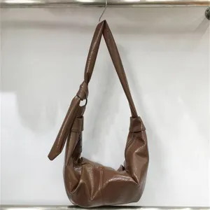 Detail view of brown PU leather hobo shoulder bag with stylish pleats and strap knot design.