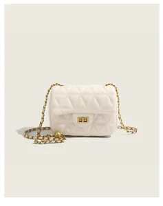 Detail shot of white quilted crossbody chain bag with stylish golden ball charm and hardware.