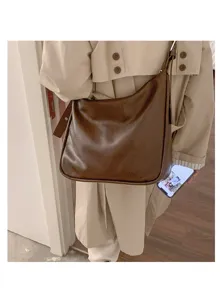 Detailed view of the brown slouchy shoulder bag worn in daily casual outfit, soft material.