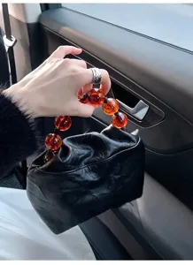 Detail view of the retro black wrinkled faux leather handbag featuring translucent amber beaded handle.