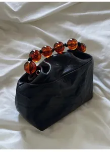 Retro Chinese style black leather crinkled handbag with vintage amber resin beaded handle detail.