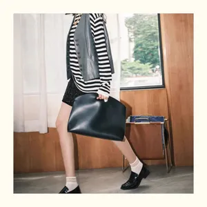 Minimalist leather laptop sleeve and business clutch bag for modern women commuting in style.