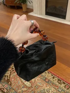 Detailed close-up view of vintage Chinese style black leather pouch with amber beads.