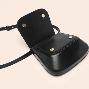 Black PU leather crossbody saddle bag with flap closure and elegant gold tone magnetic snap hardware.