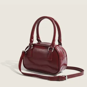 Red patent leather bowling bag for women, stylish crossbody handbag with top handles.
