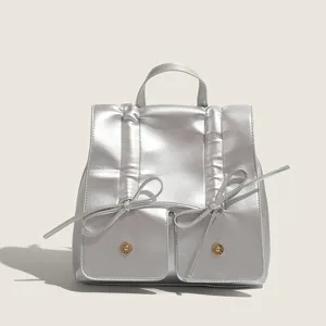 Zaino piccolo metallizzato argento con fiocchi, manico superiore e tasche, vista.