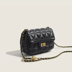 Stylish black quilted cross-body bag with gold chain strap and chic ball charm main view