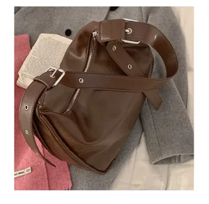 Close-up detail of dark brown vintage soft leather shoulder bag with buckle strap and zipper.
