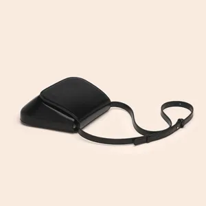 Details of the black PU leather chestnut saddle bag showing minimalist retro design and strap.