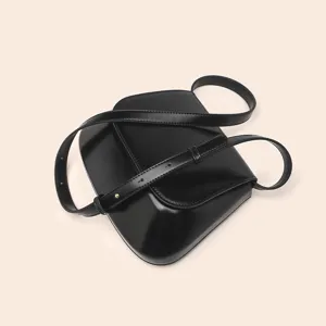 Close-up detail of the elegant black PU leather saddle bag, showing smooth texture and strap.