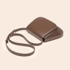 Detail shot of vintage brown PU leather saddle bag, elegant chestnut crossbody bag for women.