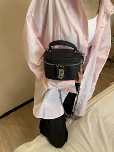 Black textured leather box vanity bag with chain strap and top handle for women fashion.