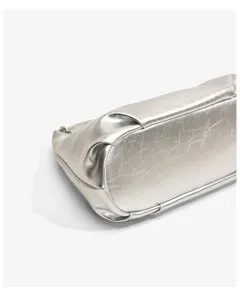 Detailed view of silver metallic commuter tote bag bottom showing crinkled leather texture.