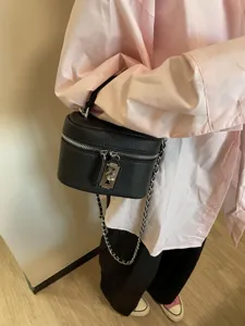 Black textured vanity crossbody bag with chain strap and metal lock detail closeup view.