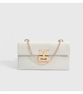Detailed view of white minimalist shoulder bag with elegant gold chain strap and geometric clasp.