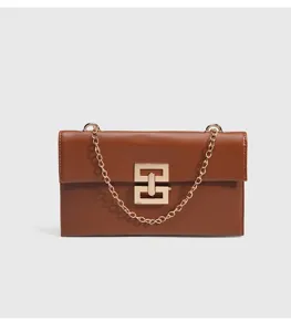Detailed view of stylish brown women shoulder bag with golden chain and geometric lock.