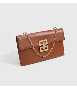 Close-up of brown crossbody bag with gold chain strap and stylish geometric metal lock.