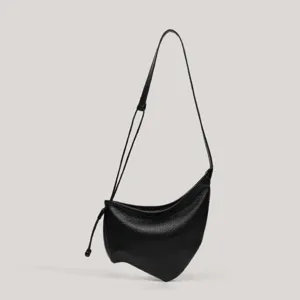 Detalle del bolso de hombro negro asimétrico, diseño elegante de cuero de moda diaria.