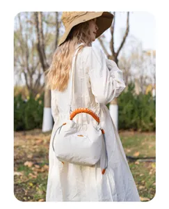 Close-up of Japanese literary quilted camera bag with orange handle and drawstring design.