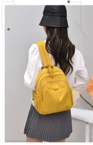 Yellow nylon mini backpack detail view, featuring multi-zipper pockets and comfortable straps.