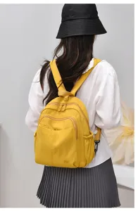 Close-up detail of lightweight yellow nylon backpack worn on back, multi-compartment style.