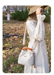 Detailed outdoor view of the quilted camera bag with orange handle and adjustable strap.