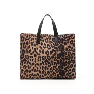 Leopard plush tote bag detail shot showing soft fluffy texture and black leather handles.