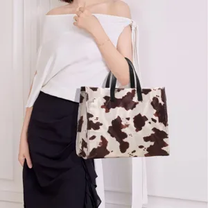Close-up detail of the fluffy plush tote bag with chic animal print and black leather handles.